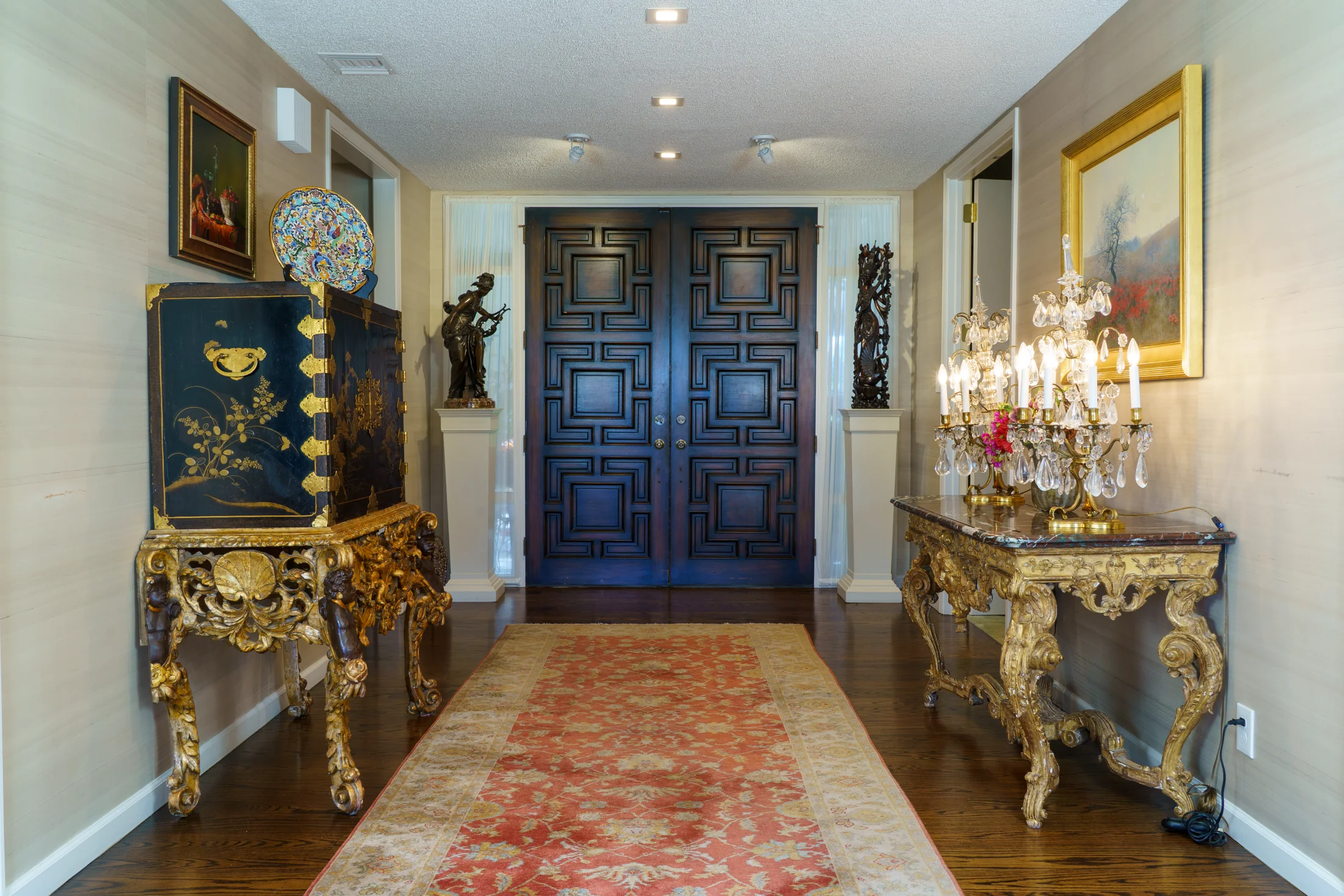 The Birnbaum collection in its home: an entryway with paintings, gilt furnishings and sculptures